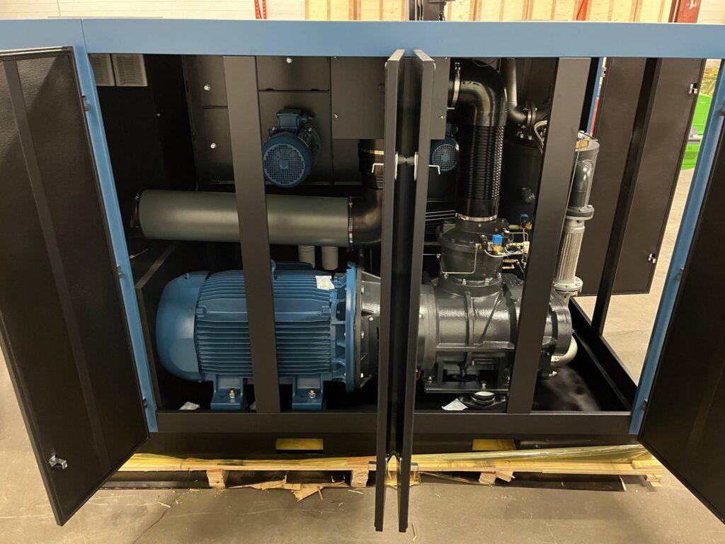 Industrial rotary screw air compressor with open cabinet showing internal parts commonly involved in compressor failure.