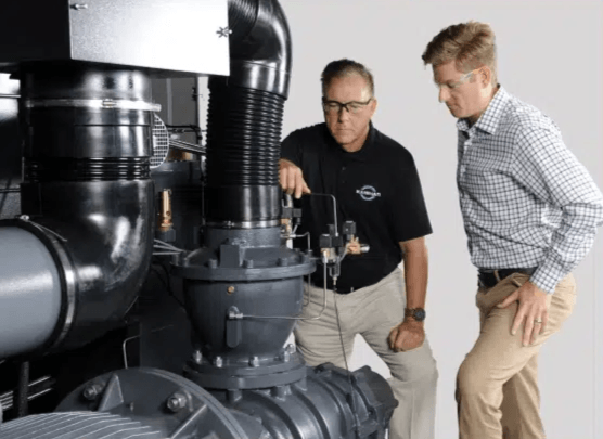 Two technicians inspecting an industrial pump component during a maintenance review